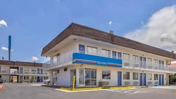 A motel with a blue awning, multiple rooms, and a parking lot.
