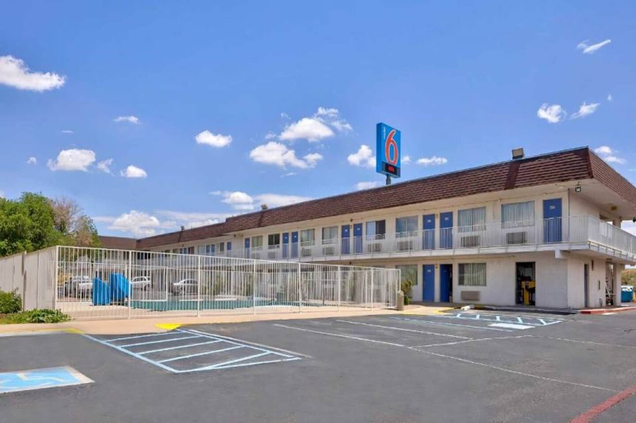 A motel with a fenced parking area and a sign indicating 6 rooms.