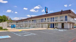 Un motel con zona de estacionamiento cercada y un cartel que indica 6 habitaciones.