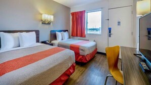 Una habitación de hotel con dos camas, un escritorio, una silla y una ventana con cortinas.