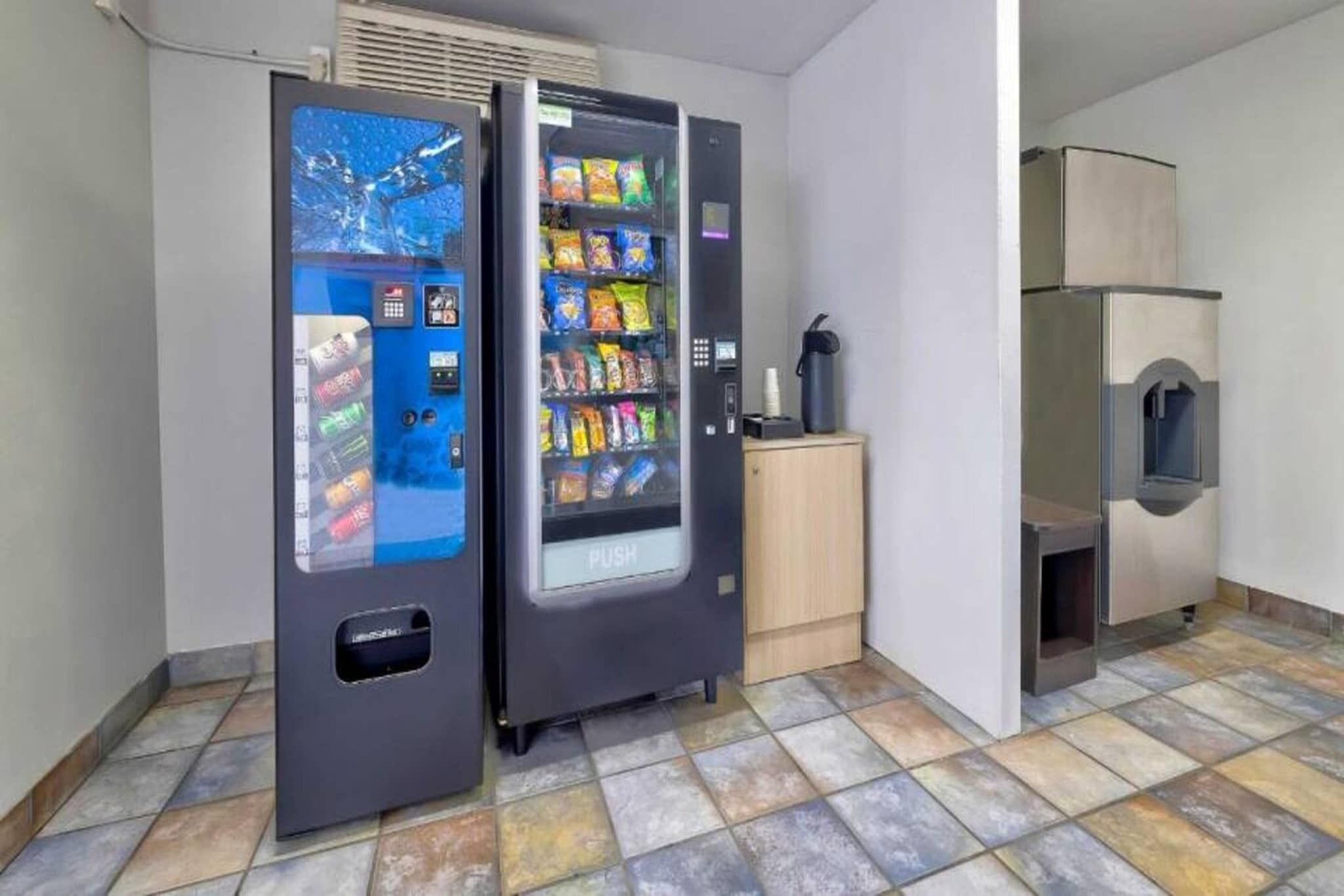 A room with two vending machines, a small cabinet, and a microwave.
