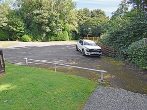 Ein weißes Auto parkt auf einer Auffahrt mit einem Metallzaun und einem Holztor.