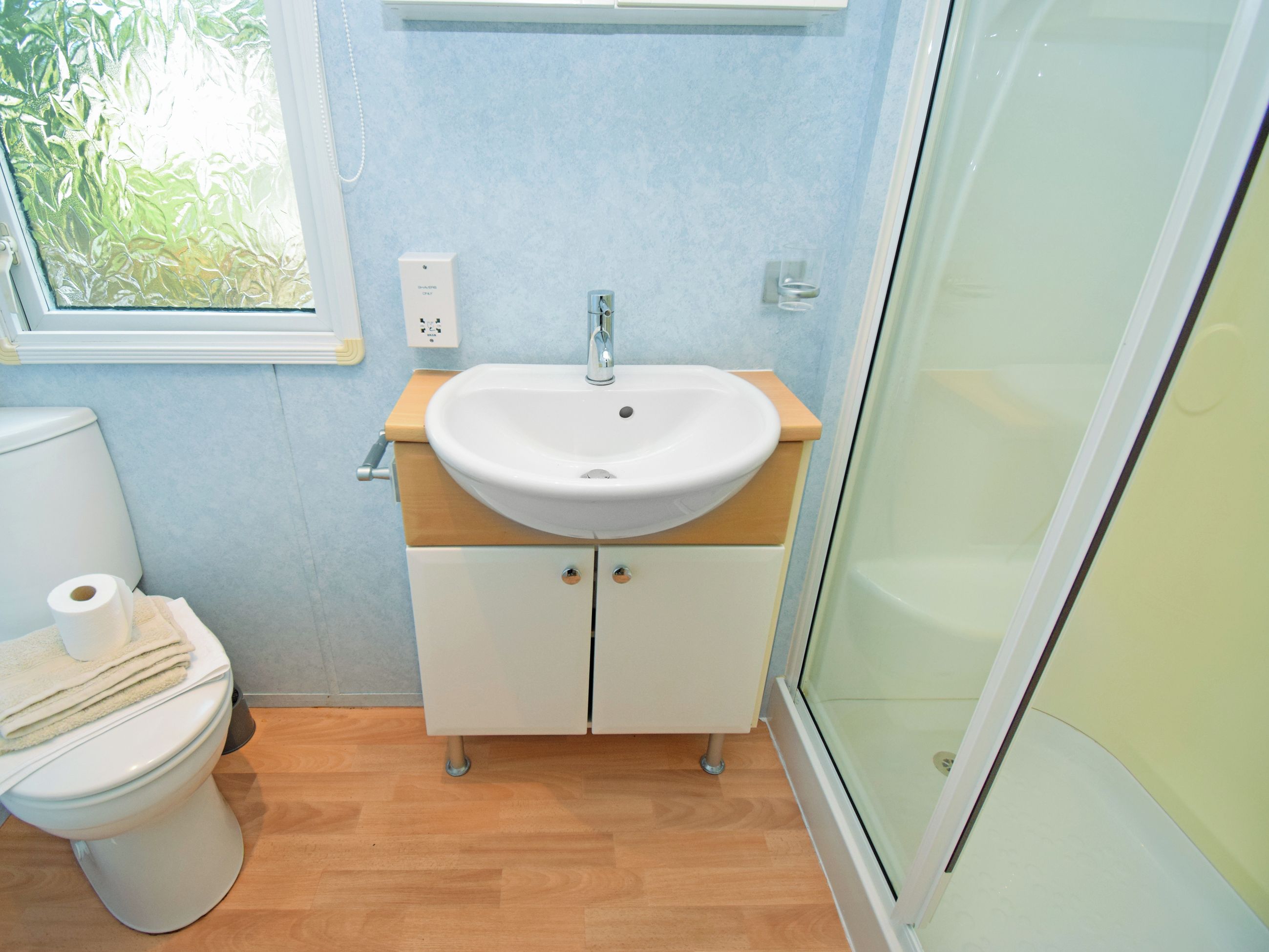 A bathroom with a white sink, wooden vanity, and a toilet.
