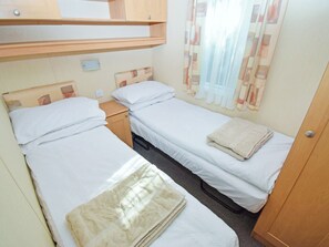 Ein gemütliches Schlafzimmer mit zwei Einzelbetten, einem Holzschrank und einem kleinen Nachttisch.