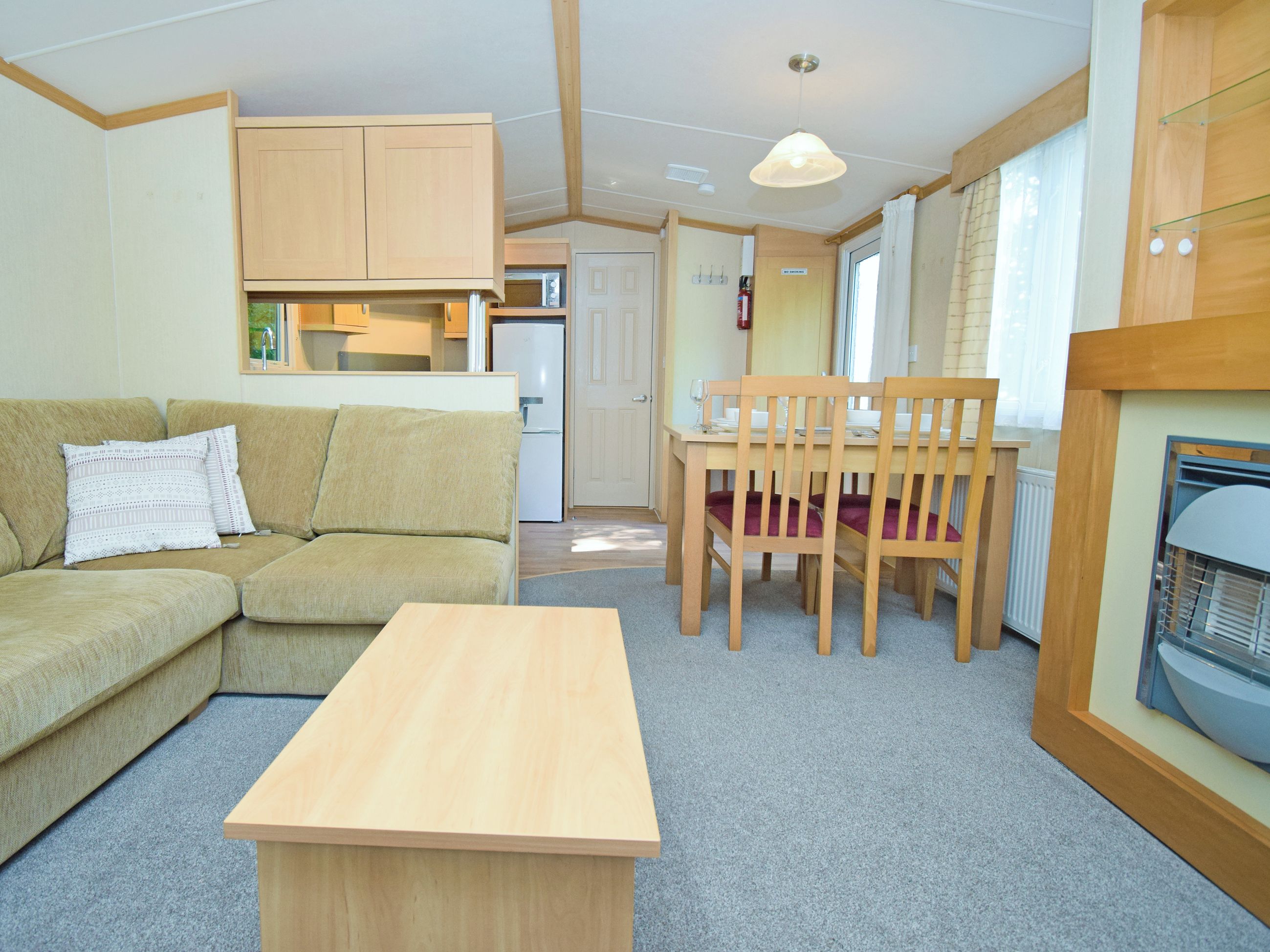 A compact living space with a sofa, a dining table with chairs, a kitchenette, and a small window.