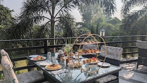 An outdoor dining area with a glass table, wicker chairs, and a tiered bread display.