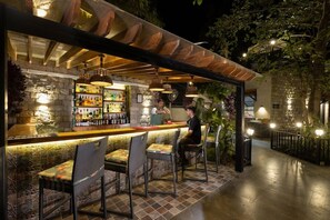 An outdoor bar area with a stone wall, bar counter, and seating. - The Golden Tusk (Ramnagar)
