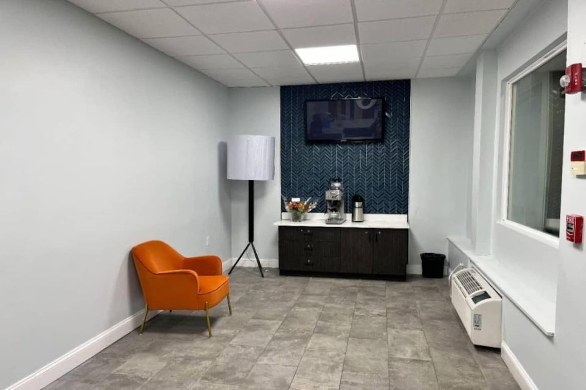 Una habitación con una silla, un escritorio, un televisor y un radiador.