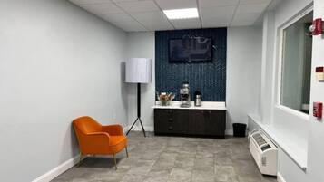 Una habitación con una silla, un escritorio, un televisor y un radiador.
