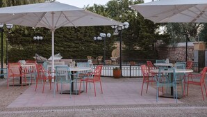 An outdoor patio area with tables and chairs, umbrellas, and outdoor lighting. - Villa Rossa Kambos (Chios)