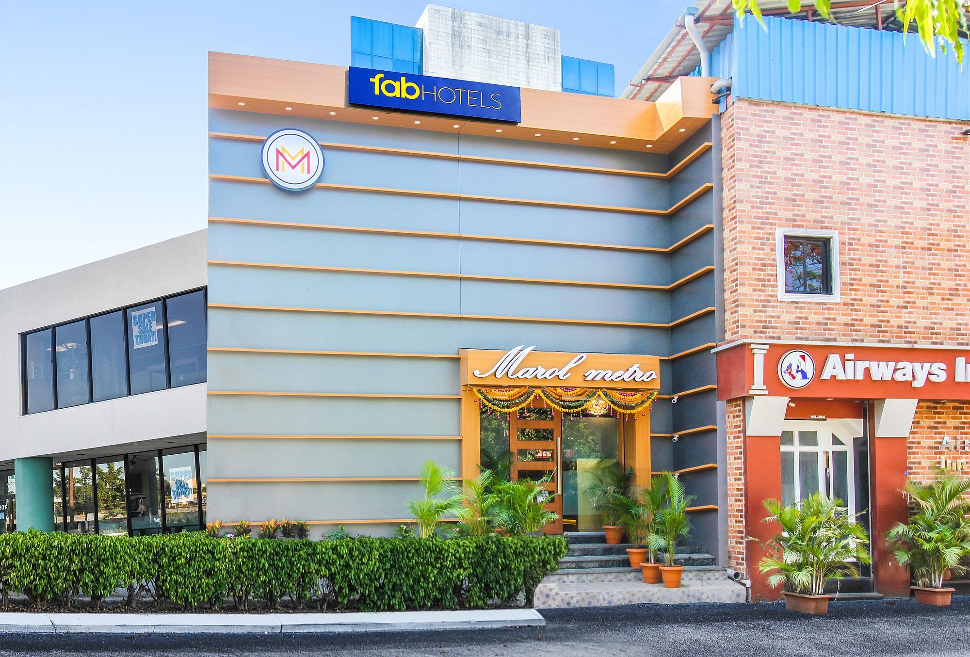 A hotel with a modern facade, a Marotel metro sign, and an Airways Inn sign.