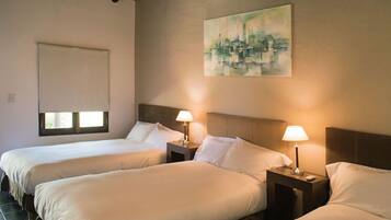 A hotel room with two beds, a painting on the wall, and a window with blinds.