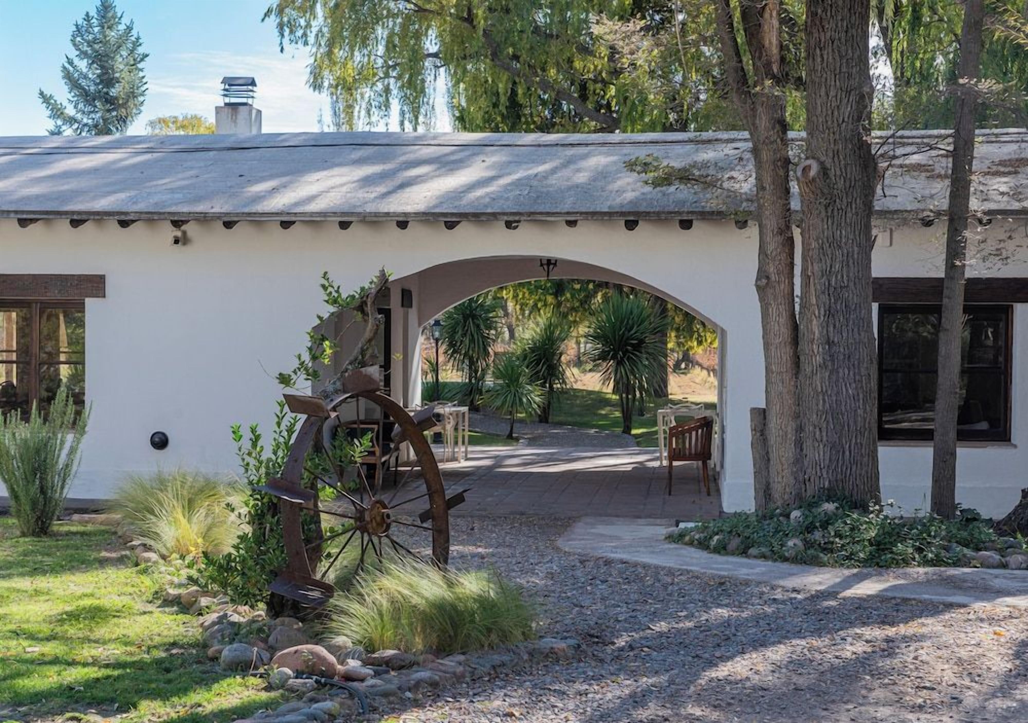 A rustic building with an arched entrance, a water wheel, and a patio area with seating.