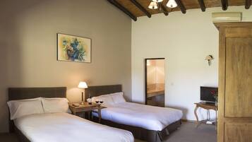 A hotel room with two beds, a nightstand with a lamp, a painting on the wall, and a wooden cabinet.