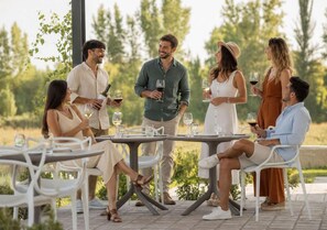 A group of people seated at outdoor tables with wine glasses, engaged in conversation. - Postales Hotel Boutique Valle del Uco (Tunuyan)