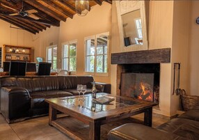 Uma sala de estar aconchegante com lareira, móveis de couro e estante de livros.