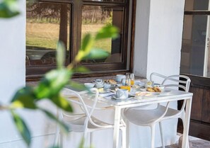 Une table de petit-déjeuner dressée avec des assiettes, des verres et un verre de jus d’orange.