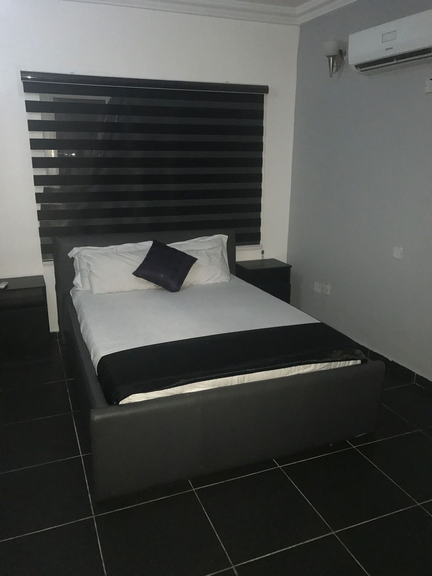 A bed with a black headboard, white bedding, and a black pillow.