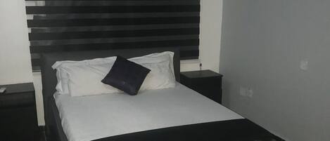 A bed with a black headboard, white bedding, and a black pillow.