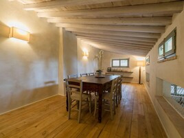 Un comedor con mesa y sillas de madera, un florero con flores y una ventana con vistas.