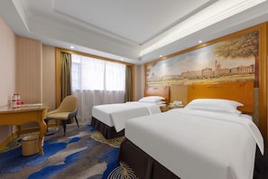 Ein Hotelzimmer mit zwei Betten, einem Schreibtisch, einem Stuhl und einem großen Gemälde an der Wand.