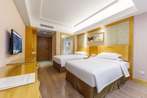 Ein Hotelzimmer mit zwei Betten, einem Fernseher, einem Spiegel und Holzboden.