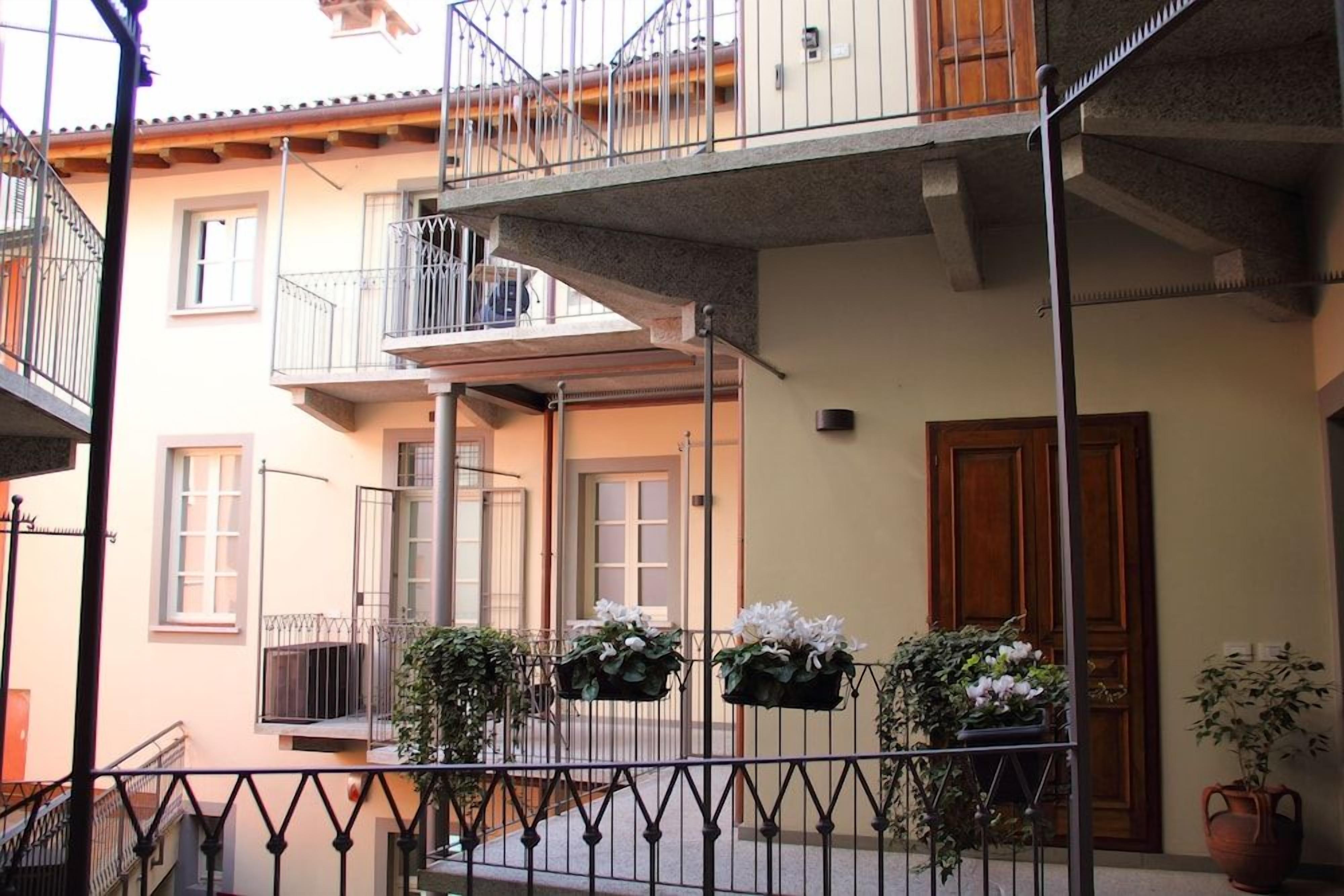 Un edificio a più piani con balconi, una porta in legno e piante in vaso.