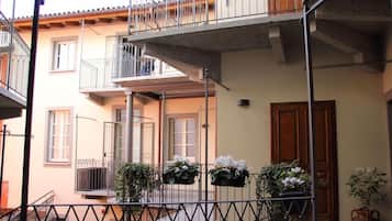 Un edificio a più piani con balconi, una porta in legno e piante in vaso.