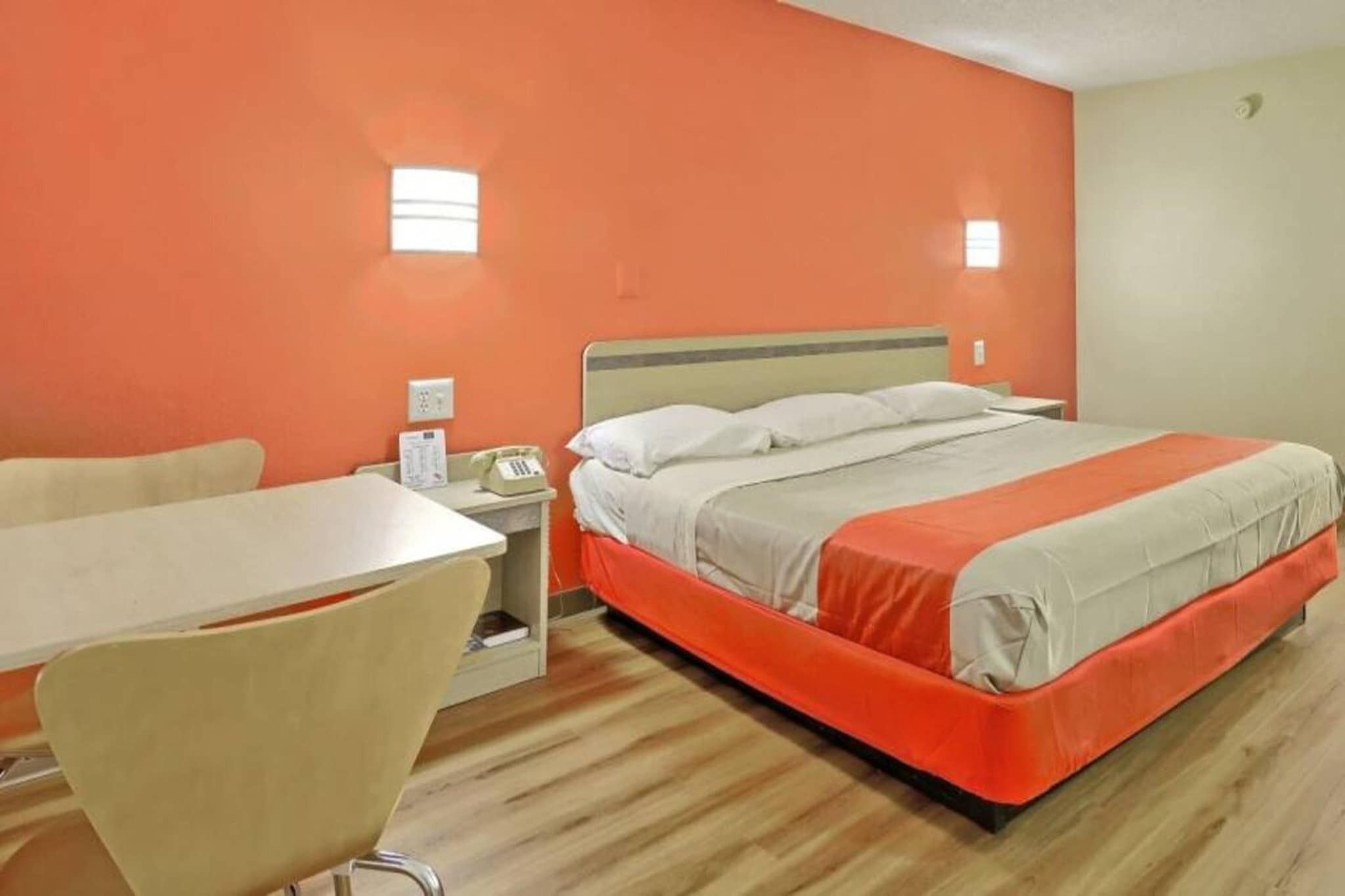 Une chambre d’hôtel avec un lit, un bureau, une chaise et un téléphone.