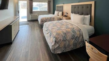 Une chambre d’hôtel avec deux lits, une télévision, un bureau et une fenêtre avec des rideaux.