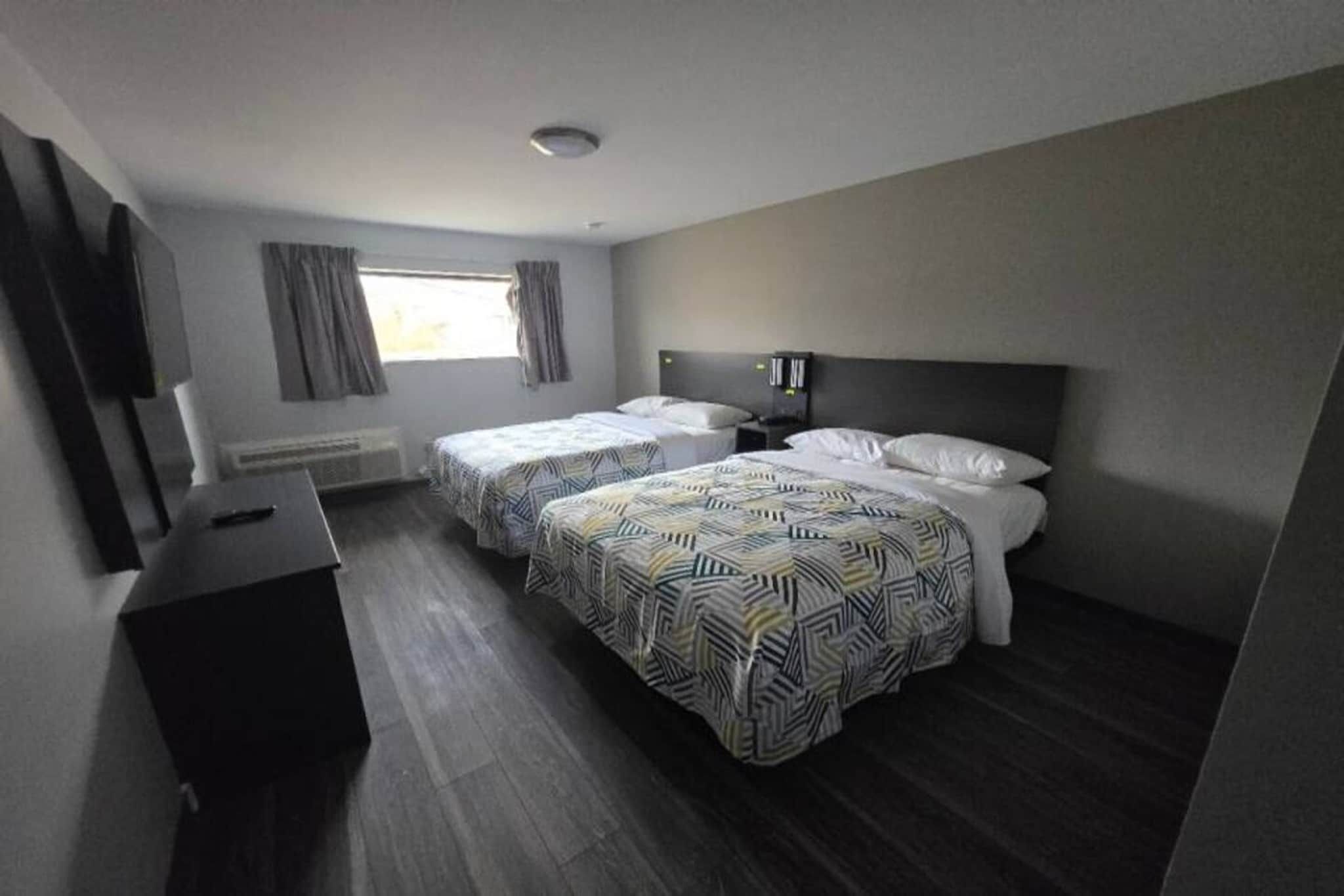 Une chambre d’hôtel avec deux lits, un bureau et une fenêtre.
