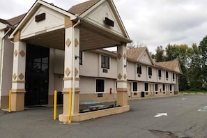 A hotel with a covered entrance, multiple windows, and a parking lot.