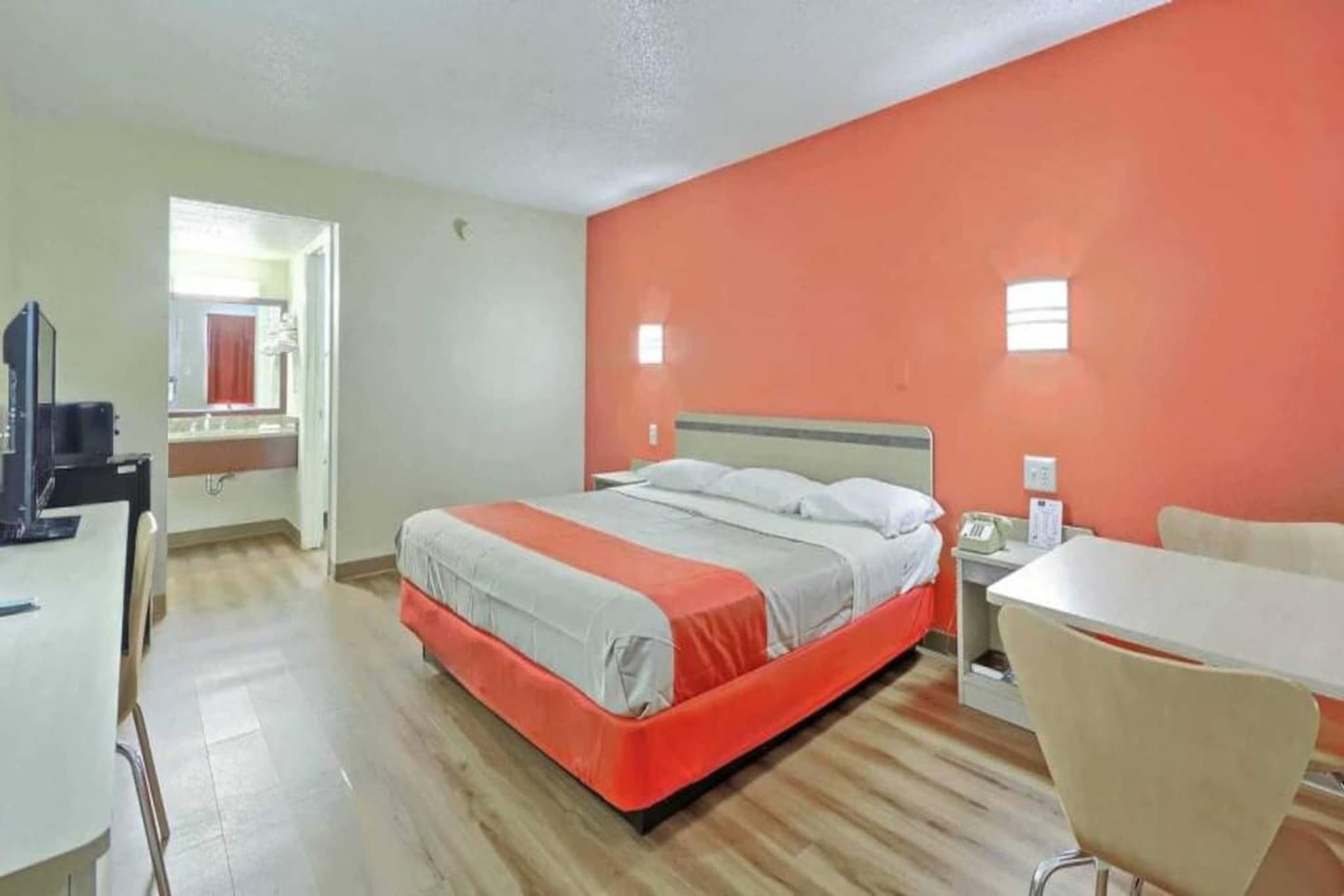 A hotel room with a bed, a desk, a chair, and a television.