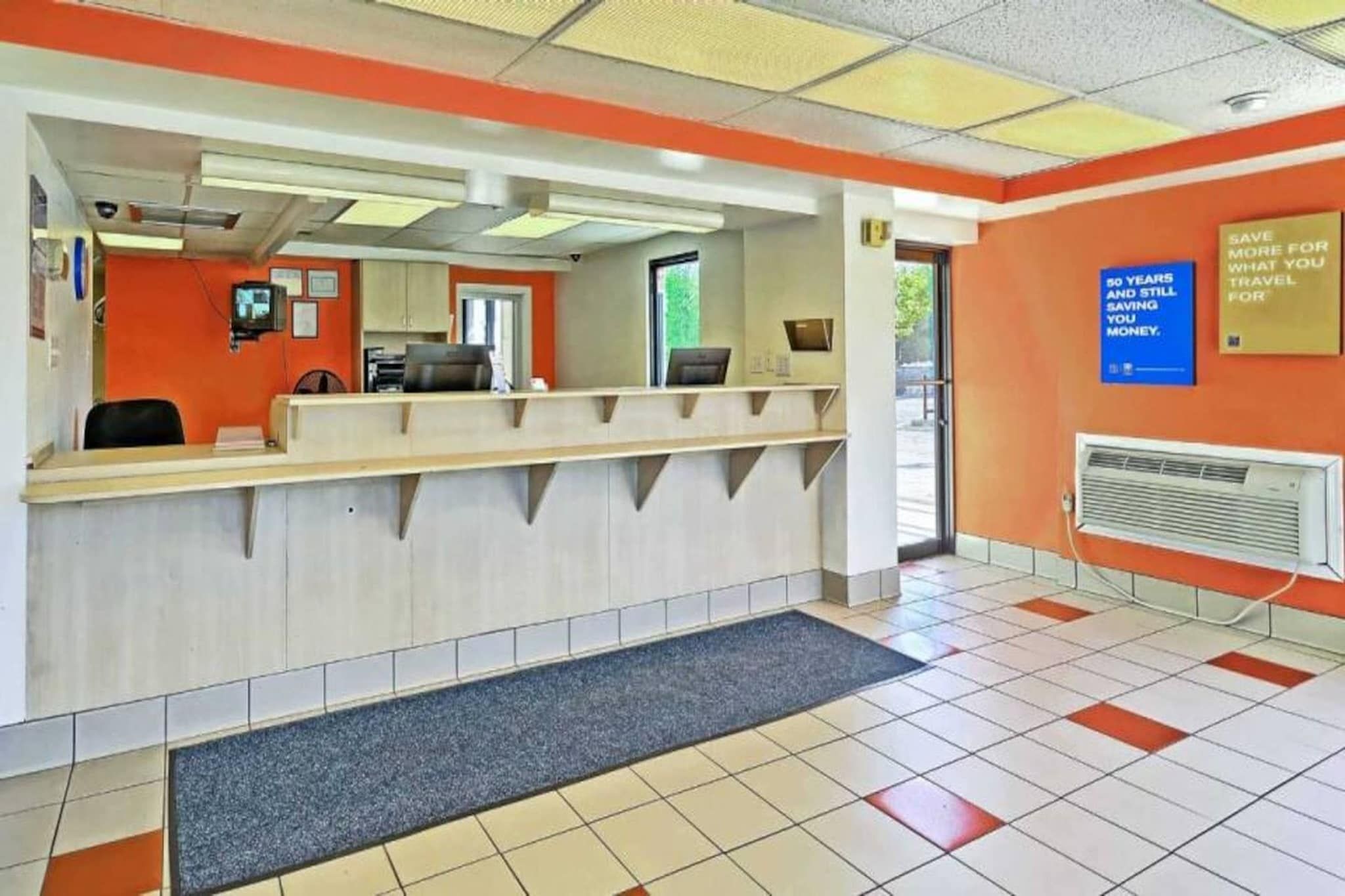 A reception area with a counter, a computer, and a wall-mounted sign.