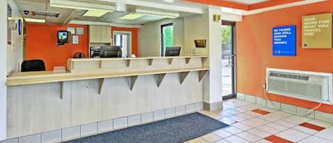 A reception area with a counter, a computer, and a wall-mounted sign.