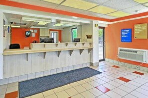 A reception area with a counter, a computer, and a wall-mounted sign. - 1 King Bed | Smoking (Maple Shade)