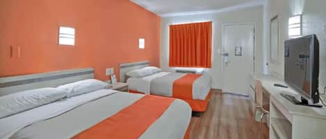 A hotel room with two beds, a television, and a window with curtains.