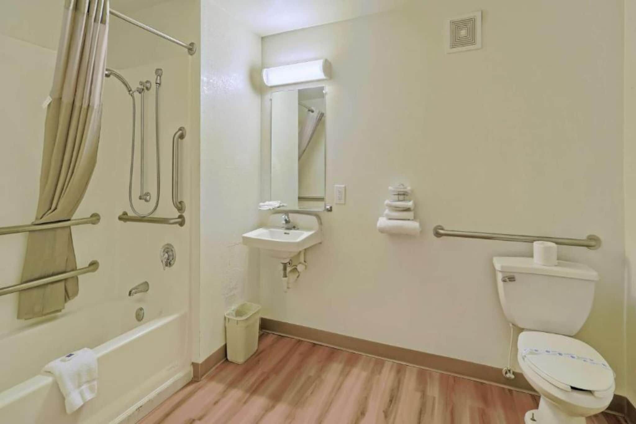 Een badkamer met een bad, wastafel, toilet en spiegel.