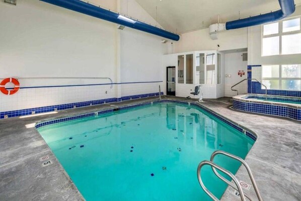 An indoor swimming pool with clear water, a lifebuoy, and a no diving sign.