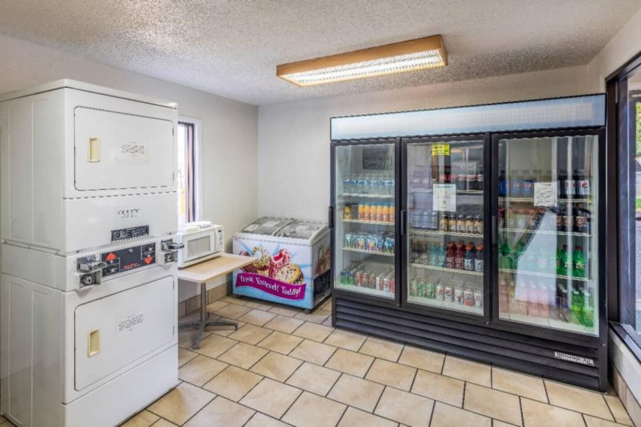 A small room with a refrigerator, microwave, and a vending machine.