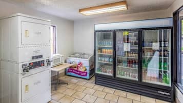 A small room with a refrigerator, microwave, and a vending machine.