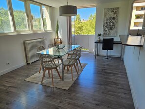 A modern kitchen with a glass dining table, wooden chairs, and a black chair. - Delightful 3-bedroom apartment in the heart of Toulouse (Toulouse)