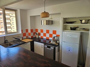 A compact kitchen with a black countertop, white cabinets, a stainless steel sink, and a white refrigerator. - Delightful 3-bedroom apartment in the heart of Toulouse (Toulouse)