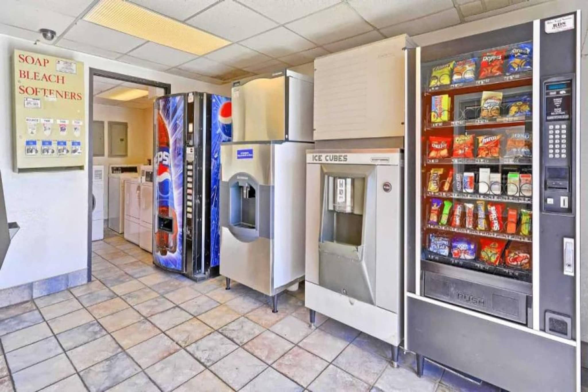 A commercial space with vending machines, a refrigerator, and a sign for soap and bleach.