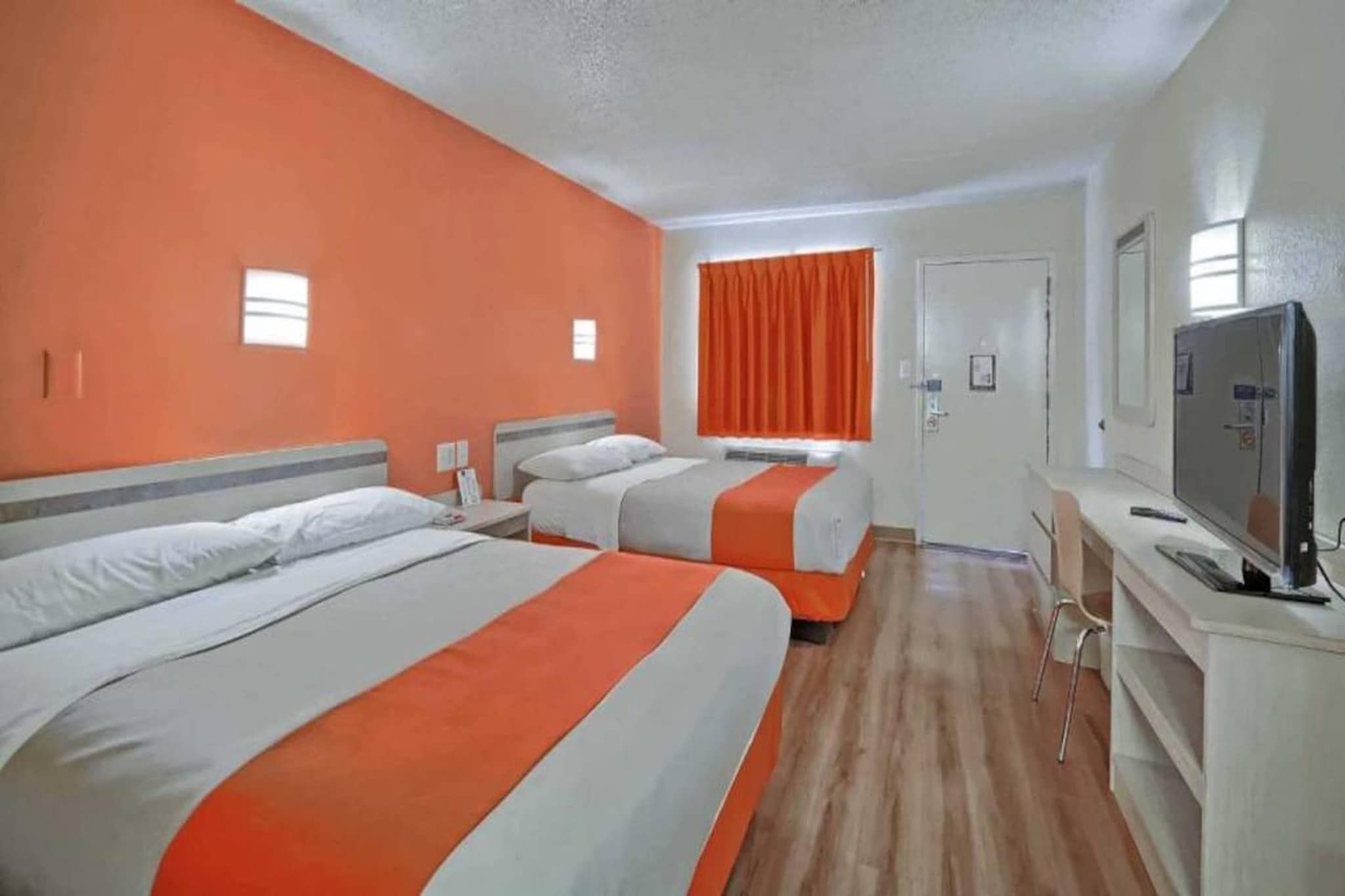 Ein Hotelzimmer mit zwei Betten, einem Fernseher und einem Schreibtisch.