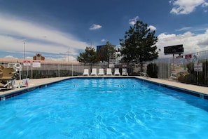 A swimming pool with lounge chairs and a fenced area. - 1 Queen Bed | Non-Smoking (Albuquerque)