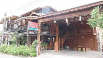 A wooden building with a sign for River Bank, featuring a covered entrance, outdoor seating, and a staircase.