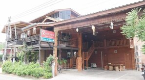 A wooden building with a sign for River Bank, featuring a covered entrance, outdoor seating, and a staircase.
