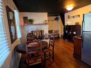 Una cocina acogedora con pared de ladrillo, mesa de madera, sillas y un refrigerador.