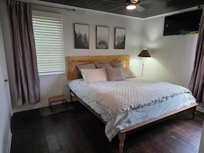 Ein Schlafzimmer mit einem hölzernen Bett, einem Nachttisch, einer Lampe und drei gerahmten Bildern an der Wand.